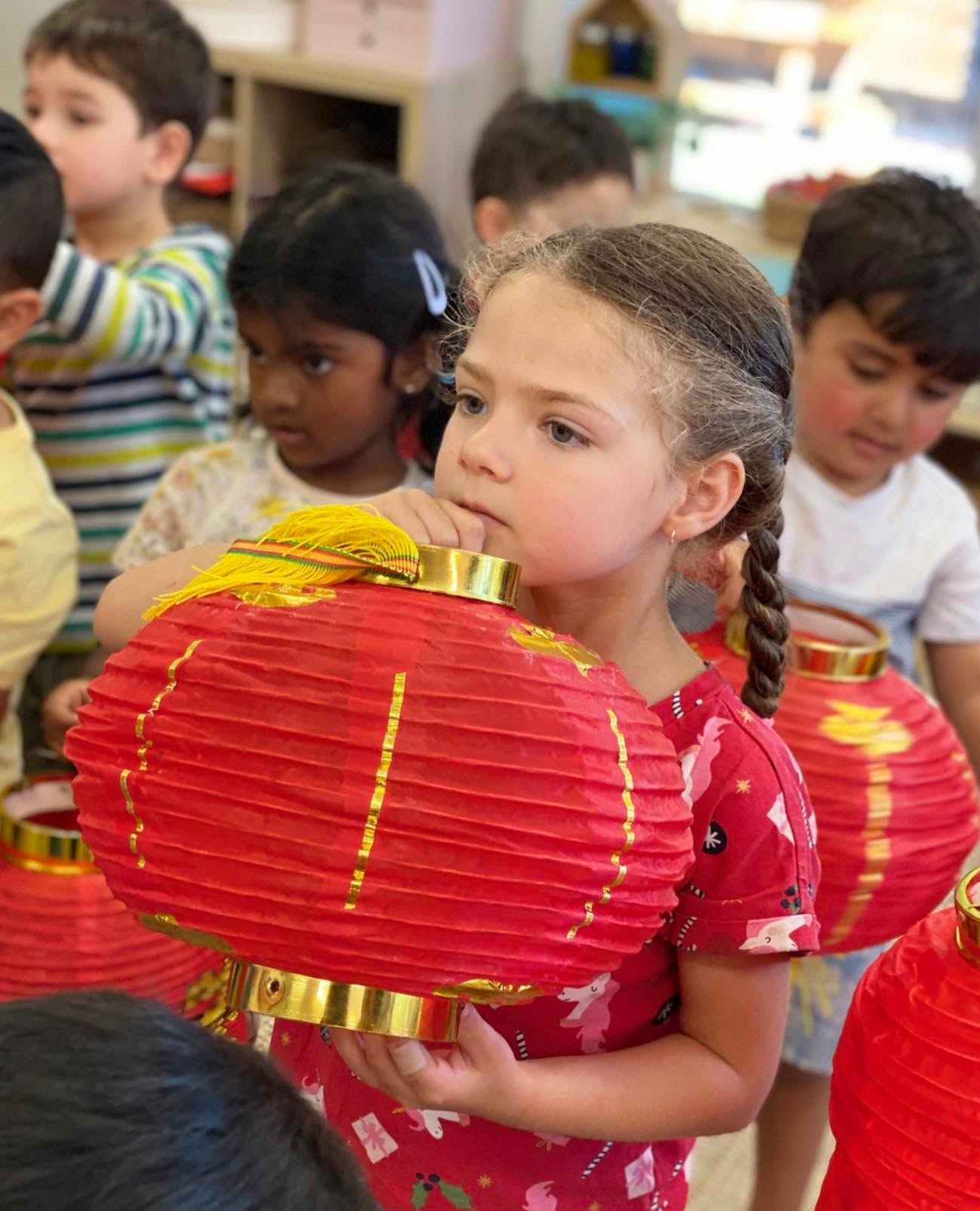 Children holding red paper lanterns for Lunar New Year at Eunoia Education