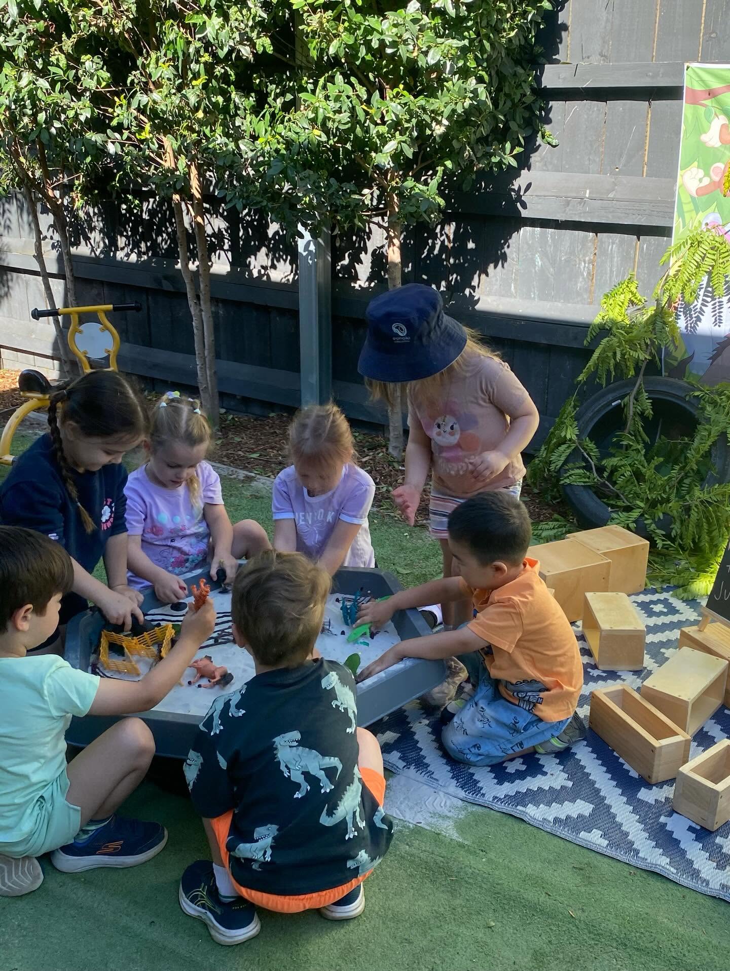 Educator and children playing with blocks on an outdoor mat at Eunoia Education